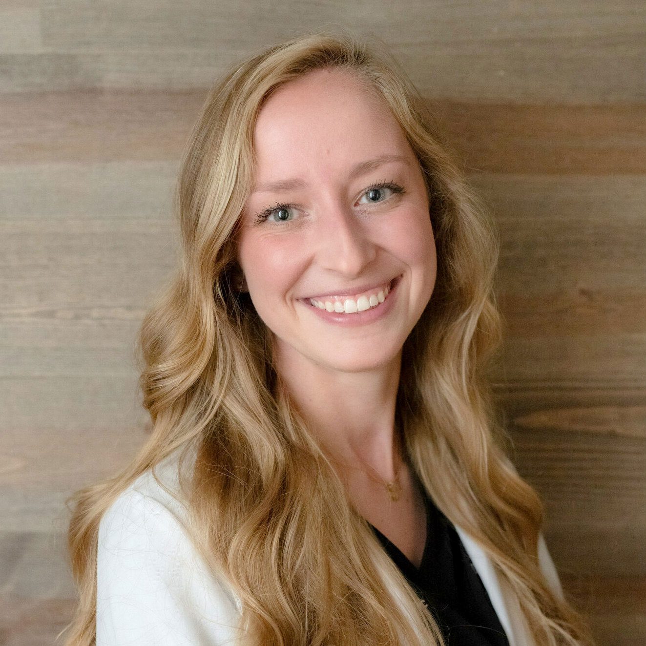 smiling female veterinarian standing in front of wood panel wall
