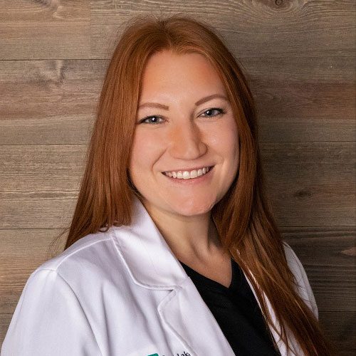 smiling female veterinarian standing in front of wood panel wall