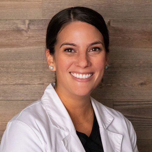 smiling female veterinarian standing in front of wood panel wall