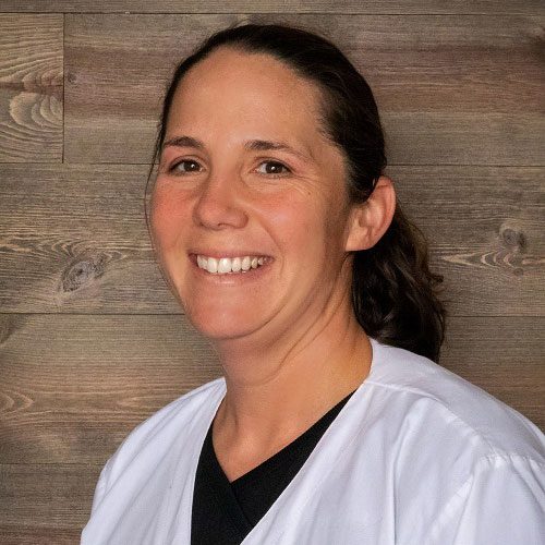 smiling female veterinarian standing in front of wood panel wall