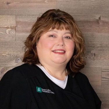 smiling woman standing in front of wood panel wall