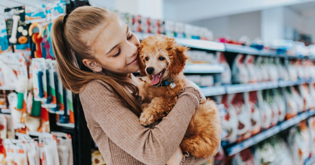 young girl holding small dog in the aisle of a pet supplies store